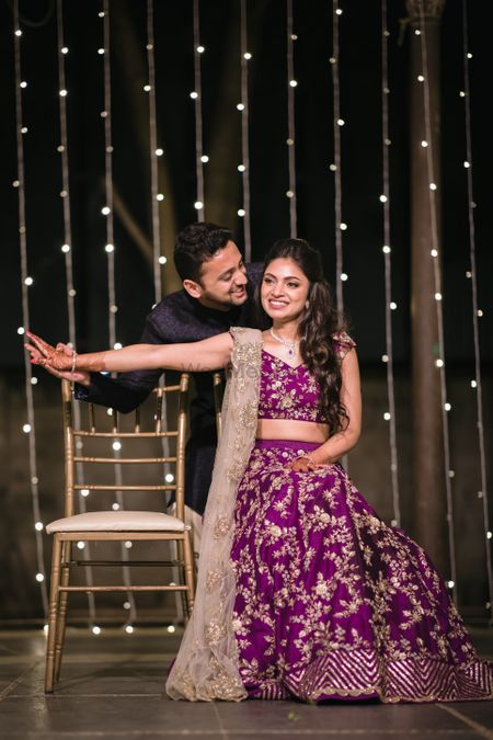 Couple portrait of a bride in aubergine lehenga and a groom in black bandhgala.