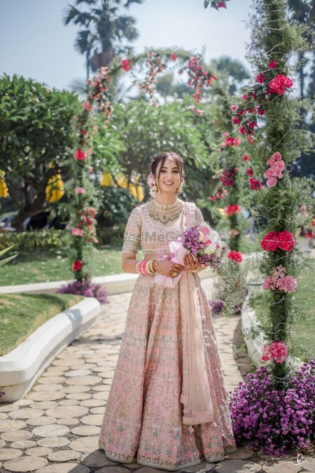 Photo of Bride dressed in a baby pink lehenga.