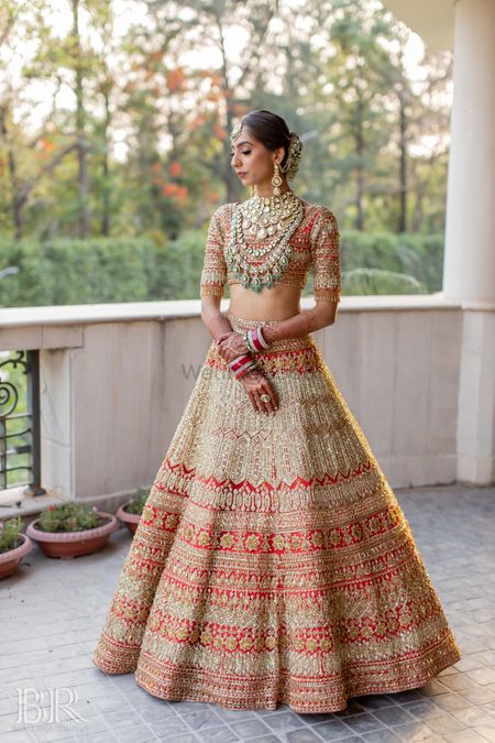 Red and gold bridal lehenga with emerald jewelelry