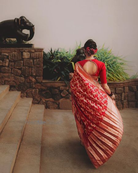 Red benarasi Sabyasachi saree with cutout blouse and a twisted bridal bun