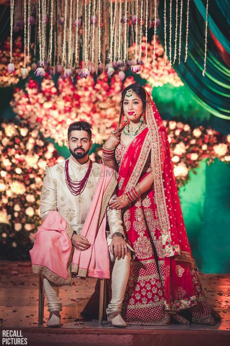 Groom in white and bride in red lehenga