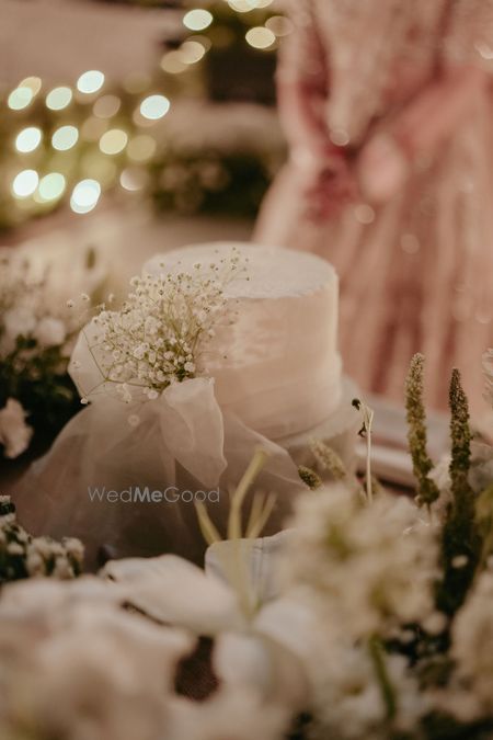 Photo of Simple white cake with a bow and baby breath on it