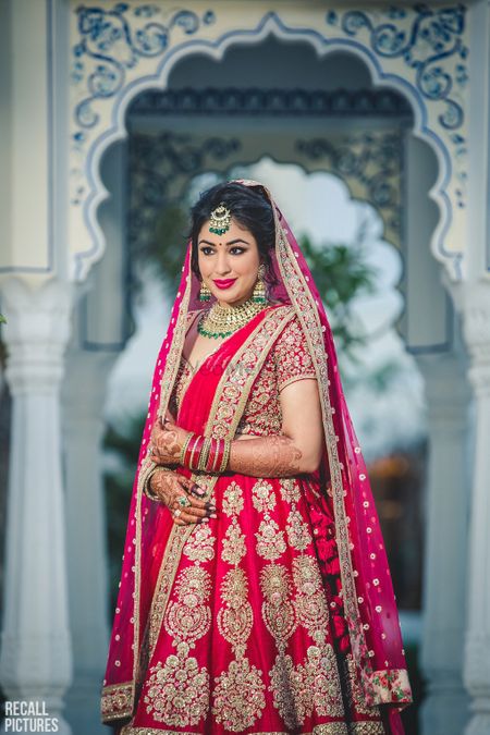 Bride in red classic lehenga with green jewellery