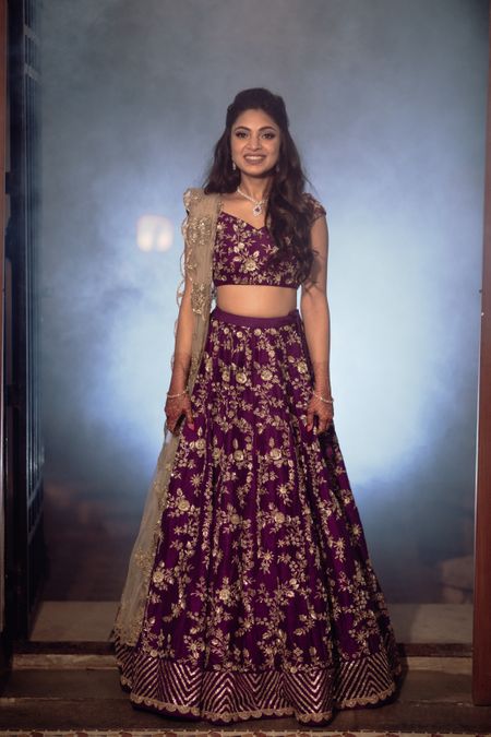Photo of Bride wearing an aubergine lehenga with a scalloped dupatta.