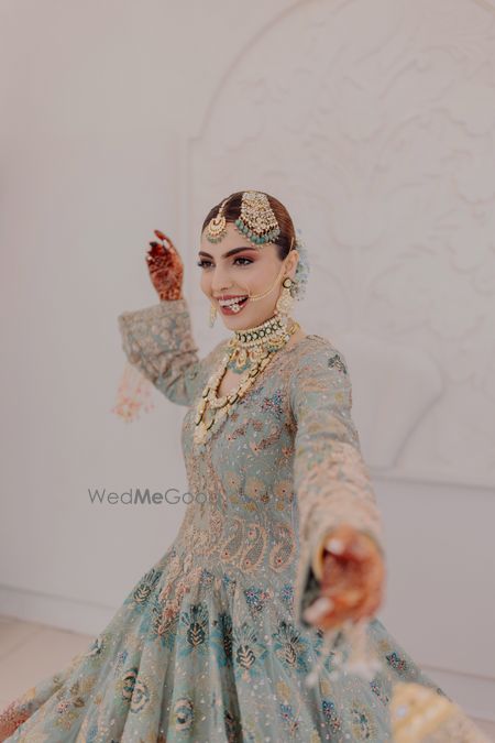 Photo of Bridal portrait on her wedding day in a stunning sea green pastel lehenga and heavy diamond and emerald jewellery