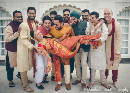 Fun bridal portrait with groomsmen picking bride up