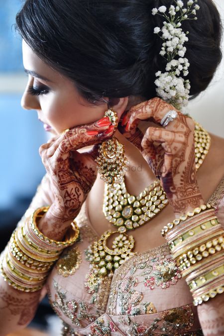 A bride wears her earrings while getting ready for her wedding 