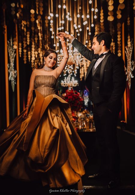 A bride in a golden gown dances with her groom on the engagement