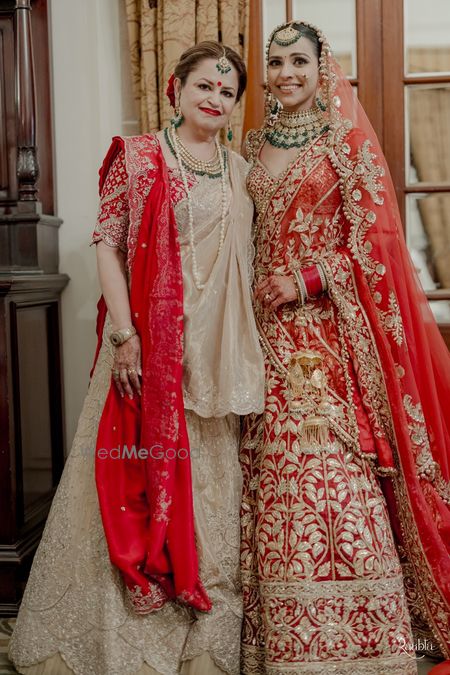 Photo of Stunning mother and daughter wedding day portrait with both of them in red and gold ensembles