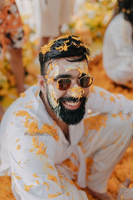 Fun haldi photo of the groom with yellow flowers on haldi day