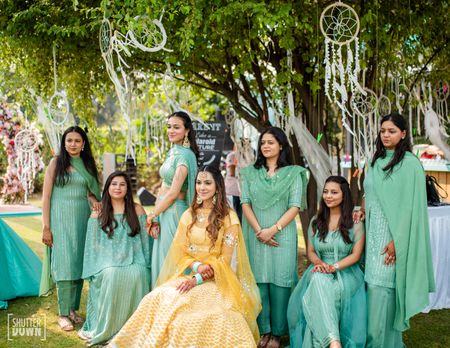 Photo of bride with bridesmaids in matching outfits on mehendi