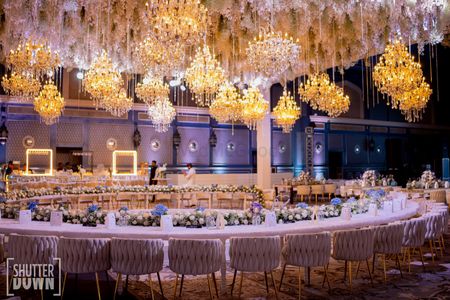 Long table setup with floral decor and gold chandeliers