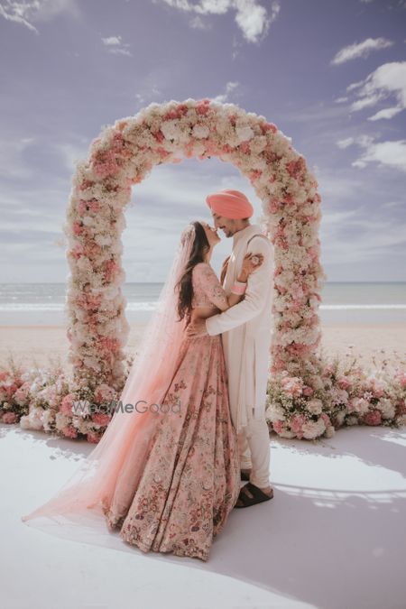 Lovely candid capture of the couple in front of a floral archway in all pastel