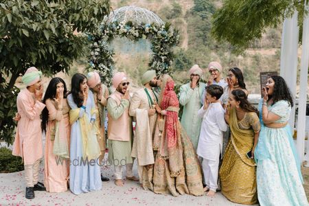 Fun family portrait with the couple kissing on their wedding day