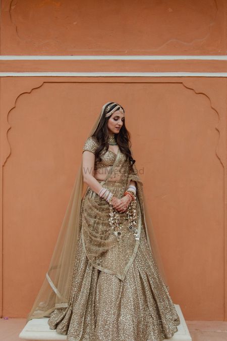 Classic bridal portrait with open hairstyle, gold lehenga and a double sispatti