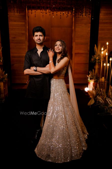 Couple portrait with the bride in a shimmery gold lehenga and groom in an all-black ensemble