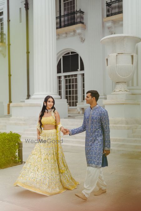 Bride in a yellow lehenga with white work and groom in a fresh blue kurta for their mehendi