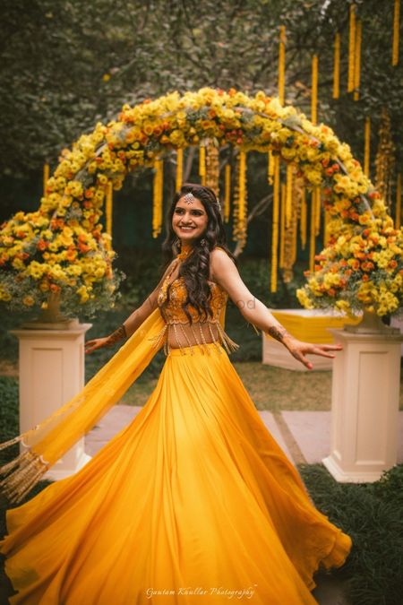Photo of Bride twirling in yellow mehendi lehenga