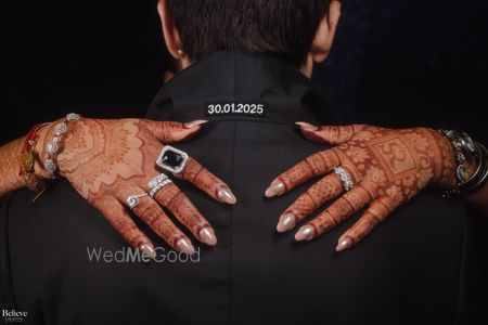 Photo of Fun customised wedding date on the groom's tuxedo with bridal hands on his shoulders