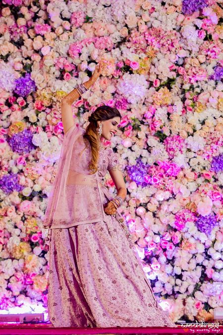 Bride dancing against a floral backdrop on stage