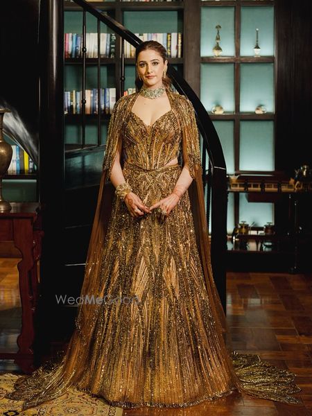 A cape style deep gold lehenga with layering by Manish Malhotra for Nupur sanon's sangeet look