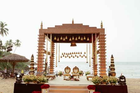 Photo of Gorgeous beach side mandap with hanging brass bells and open air venue
