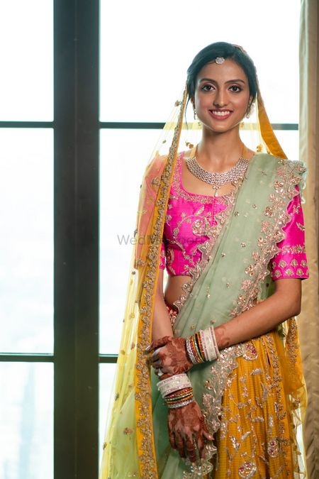 A bride dressed in a yellow and pink lehenga at her wedding