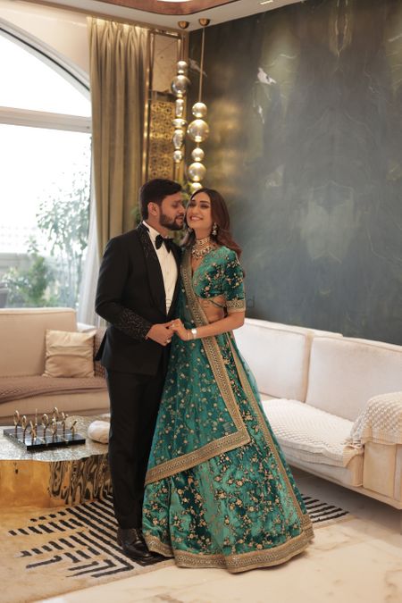 Cute couple photo with the groom in a tuxedo and bride in a teal blue velvet lehenga