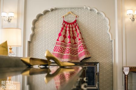 Bridal lehenga in red on a hanger in the room