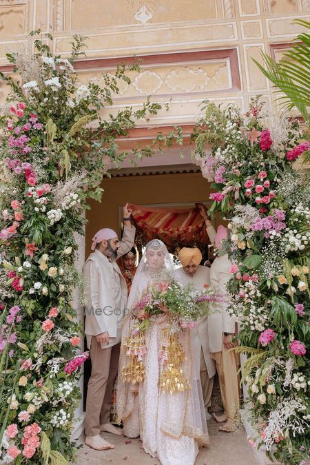 Photo of Lovely capture of the bride entering on the wedding day under a floral entrance