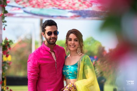A couple in color-coordinated outfits for their mehndi ceremony