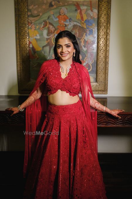 Photo of Fun all red lehenga for sangeet with topaz and diamond jewellery for the bride with a cape