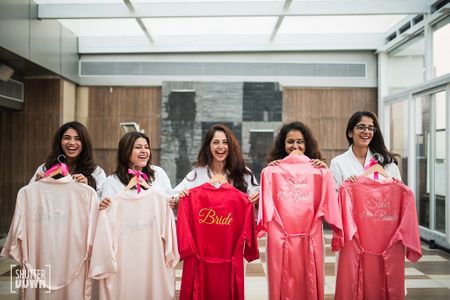 Bride with bridesmaids holding up personalised robes 