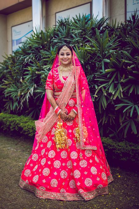 A beautiful bridal portrait in a bright pink lehenga and gold jewellery. 
