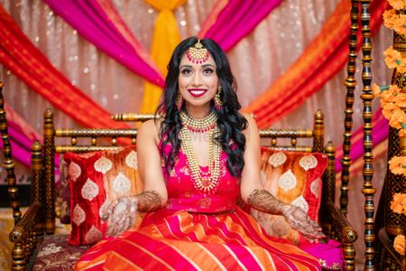 bridal mehendi look in orange and pink leheriya lehenga