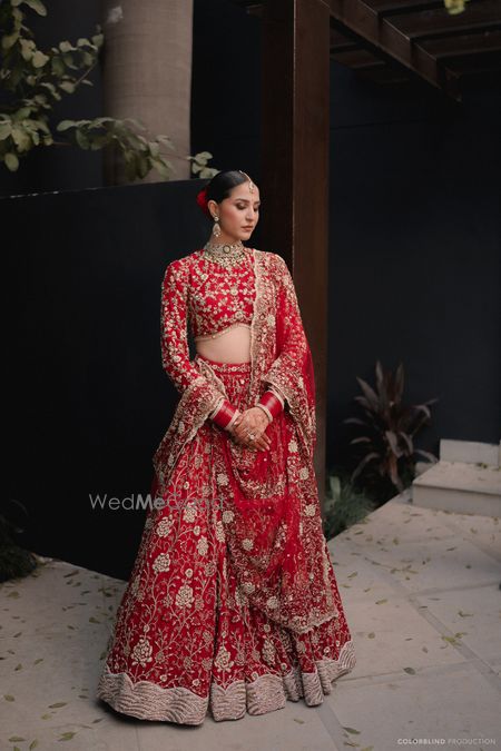 Stunning all-red lehenga with gold work, sleek hair bun and full sleeved blouse for the wedding day 