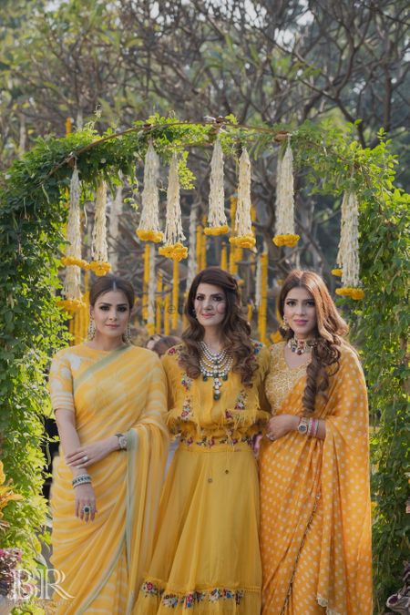 bride and her sisters in matching yellow outfits on mehendi