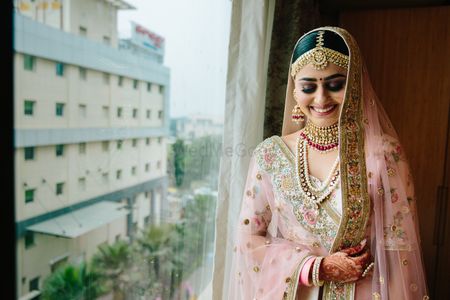 A bride in a soft pink lehenga and gold jewelry