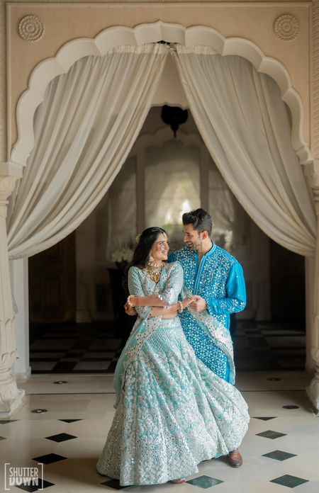 Bride and groom in co-ordinated blue outfits with a bride in a tiffany blue lehenga and groom in aqua blue sherwani