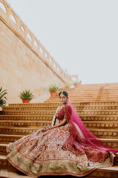 Bride sitting on the staircase with her lehenga all flare-out.