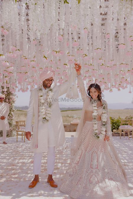 Happy just-married couple portrait with mandap decor in white and pink