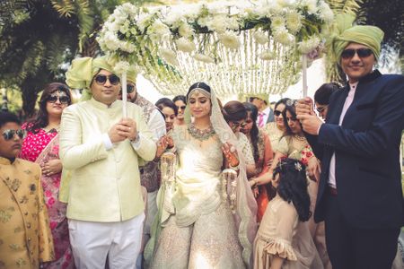 A gorgeous bridal entry with the bride under a white phoolon ki chaadar
