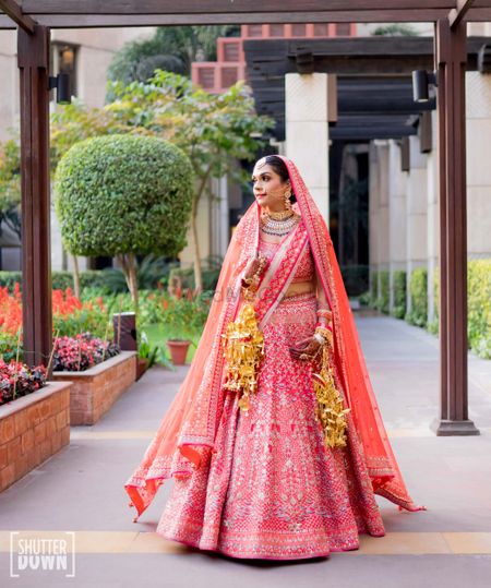 A bride in a red lehenga with gold kalire and double dupatta