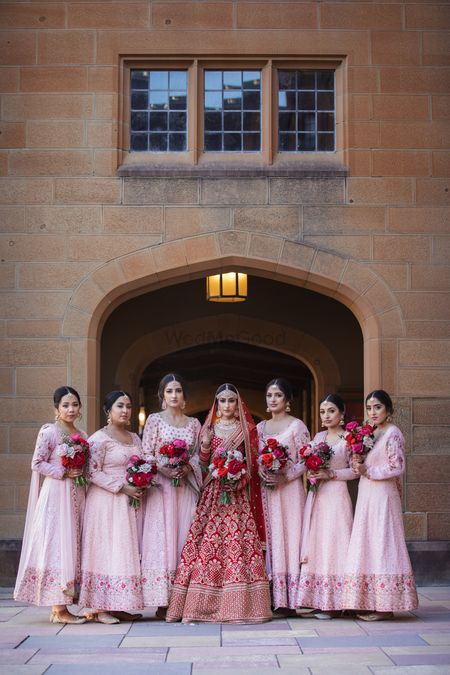 A bride in red with bridesmaids in light pink 