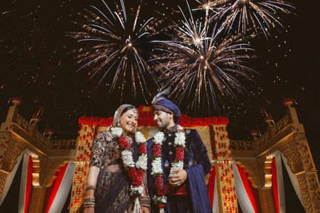 A couple poses infront of fireworks on their wedding day