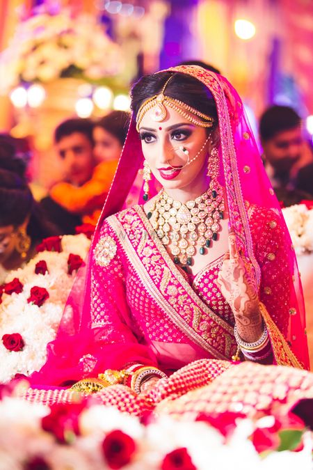 Photo of Bride dressed in a red lehenga posing while making an entry.