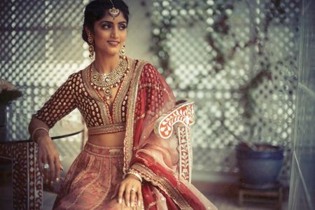 A groom's sister posing in a red lehenga on their engagement day 