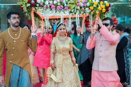 bride in gold lehenga entering under phoolon ka chadar