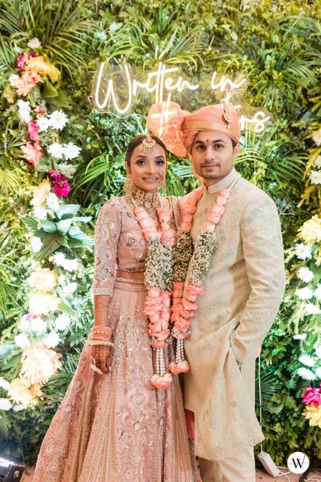Photo of matching bride and groom in peach with babys breath jaimala