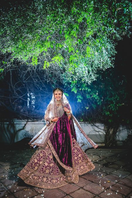A bride in a velvet lehenga and double dupatta twirls on her wedding day